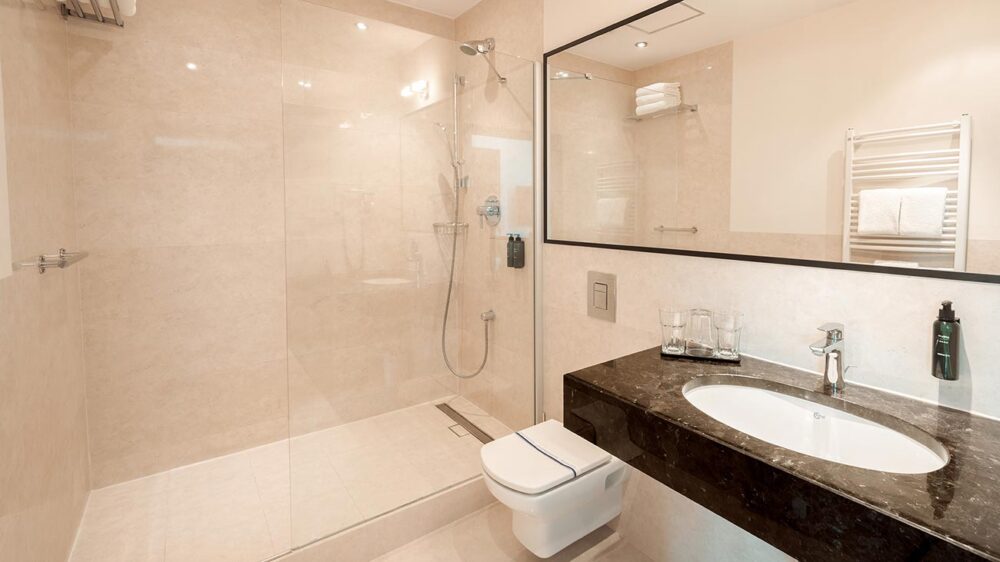 bright bathroom with a shower, large mirror, and black sink